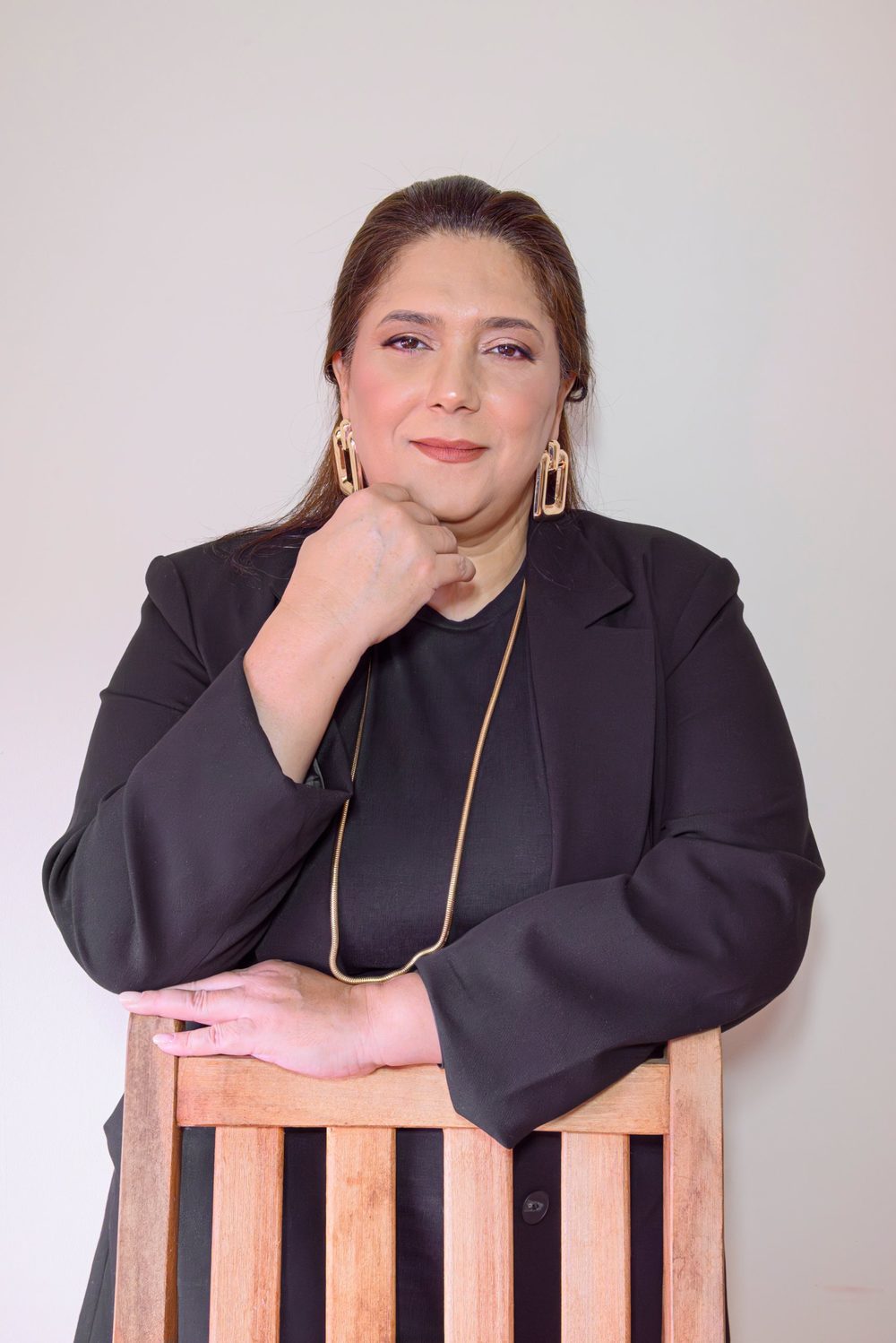 Retrato de Adriana Delgado apoiada em uma cadeira de madeira